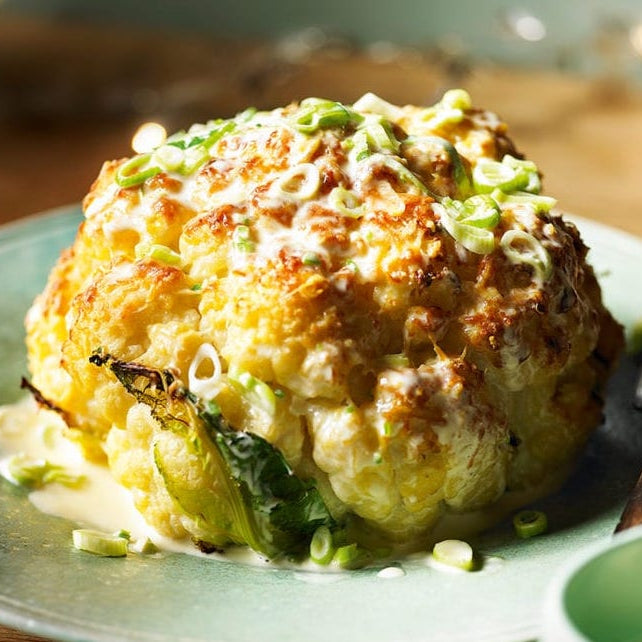 Whole roasted cauliflower with cheddar and spring onion sauce